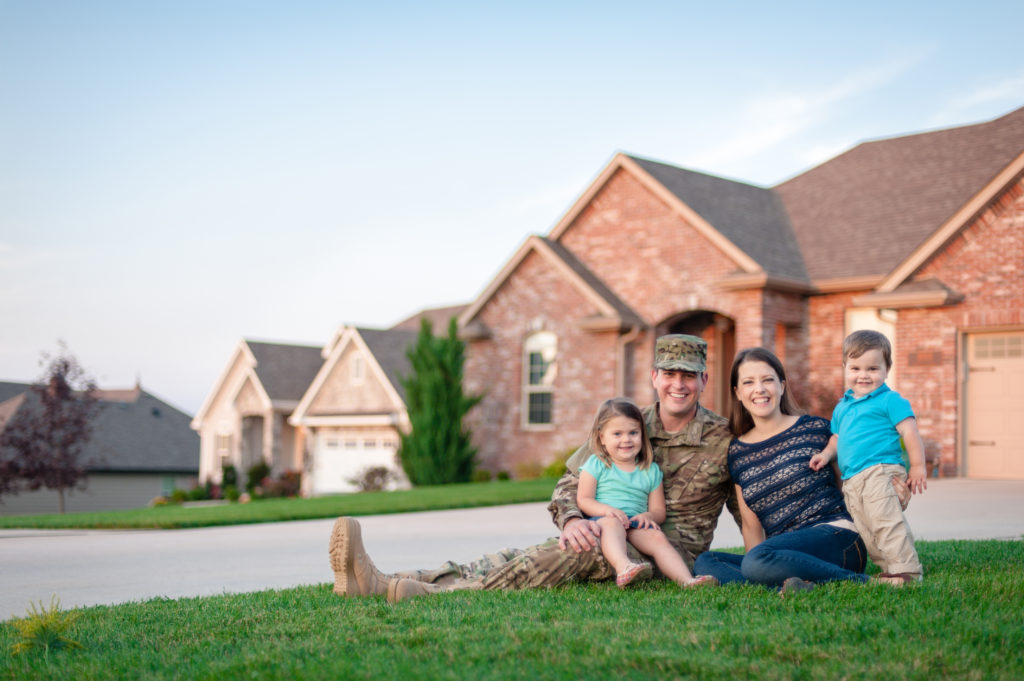 Military veteran and his family sitting on the front lawn outside their home