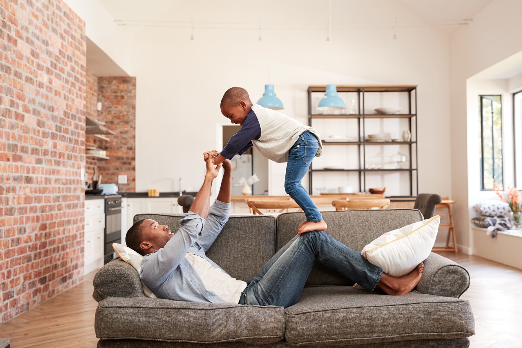 Father and son playing on a couch in their living room.